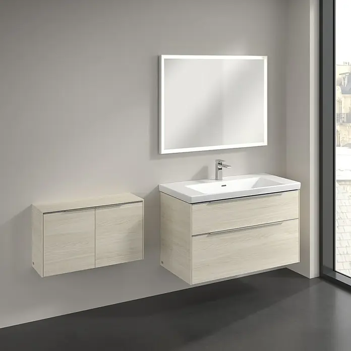 Villeroy & Boch Subway 3.0 Seitenschrank - B x T x H: 72,8 x 25,6 x 42,3 cm, White Oak, DIN Anschlag: Links/Rechts, Farbe Griff: Volcano Black - Ein Badezimmer-Interieur mit einem schwebenden Waschtischunterschrank und einem passenden Spiegelschrank in hellem Holzdekor.