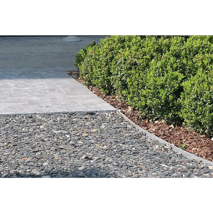 Oase Beeteinfassung & Teichrand PondEdge - L x H: 25.000 x 7 mm, Breite: 140 mm - Ein Gartenweg mit grauen Steinen und gepflastertem Rand, neben einem gepflegten grünen Busch, bietet eine natürliche und elegante Gartengestaltung.