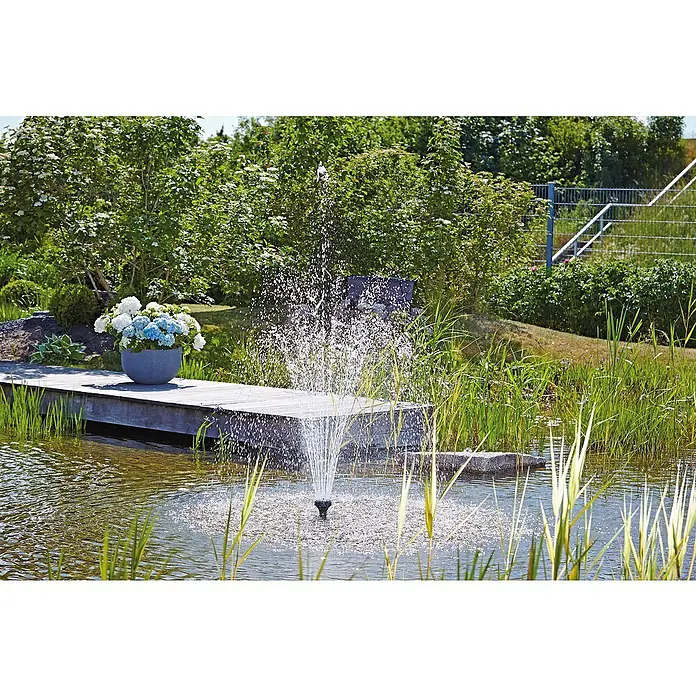 Oase Fontänenaufsatz Vulkan 37 - 2,5 K - Kunststoff, Max. Förderhöhe: 450 cm - Ein beruhigender Gartenteich mit einer sprudelnden Springbrunnen-Düse in der Mitte, umgeben von üppigem Grün und bunten Blumen.