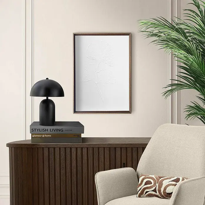 Reinders Bild Craft Art - Ginkgo, B x H: 30 x 40 cm - Nahaufnahme eines stilvollen Wohnzimmers mit Fokus auf einem gerahmten Pflanzenkunstdruck über einer Holzkommode mit Lampe und Büchern.