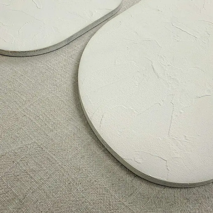 Reinders Bild Relief Art - Organic Blocks Weiß, B x H: 50 x 70 cm - Nahaufnahme von zwei runden, weißen Untersetzern mit rauer Textur auf einem beigen Stoff. Die Oberfläche der Untersetzer wirkt handgefertigt.