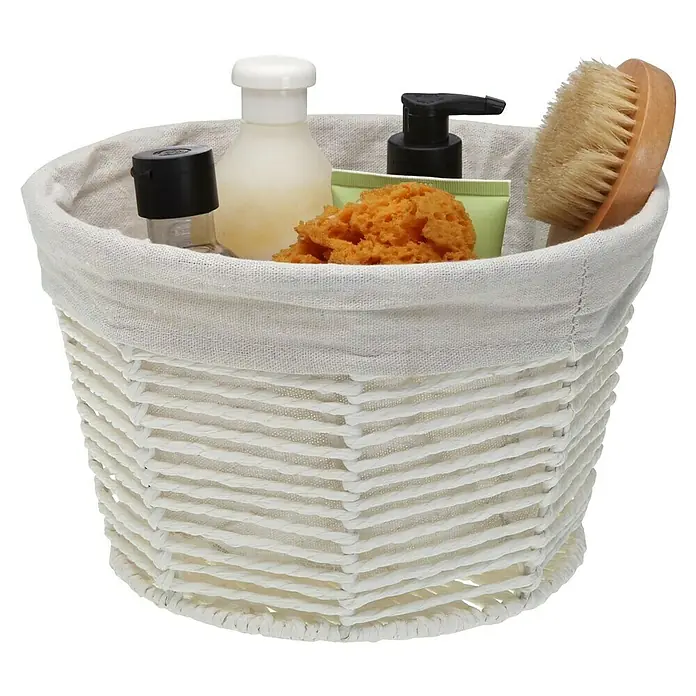 Versa Cesta redonda - Ø x Al: 25 x 15 cm, Blanco - Una cesta blanca llena de varios productos de baño como loción, esponja y cepillo, perfecta para la organización del baño.