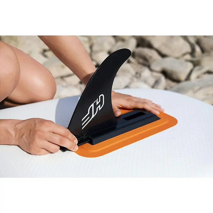 Bestway Hydro Force Juego de paddle surf Aqua Journey - L x An x Al: 274 x 76 x 12 cm, Carga útil: 100 kg, Hinchable, Naranja/Blanco - Primer plano de una persona que sujeta una aleta de surf negra con un logotipo blanco a una tabla de surf blanca.