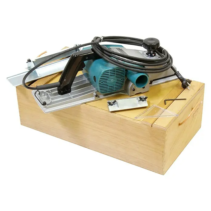 Makita Elektrohobel 1806B - 840 W, Leerlaufdrehzahl: 0 U/min - 16.000 U/min - Bild einer Hobelmaschine von Makita, die auf einer Holzkiste steht. Das Gerät ist blaugrün und schwarz.