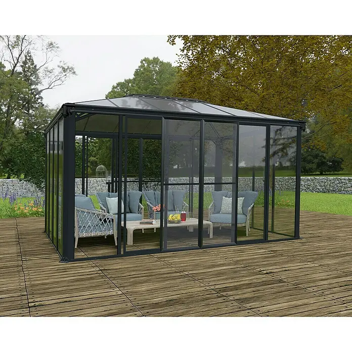 Palram – Canopia Gartenpavillon Ledro 4300 - B x T: 295,5 x 430 cm, Aluminium, Anthrazit - Einladende Outdoor-Lounge unter einem eleganten Pavillon mit Glaswänden und bequemen Sitzmöbeln auf einer Holzterrasse.