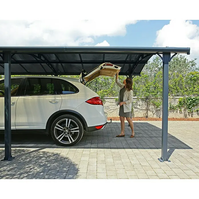 Palram – Canopia Carport Arcadia 4300 - Außenmaß inkl. Dachüberstand (B x T): 3,59 x 4,35 m, Doppelcarport, Grau - Frau unter Carport neben weißem Porsche Cayenne. Der Carport bietet zuverlässigen Schutz vor Witterungseinflüssen und Beschädigungen für Ihr Fahrzeug.