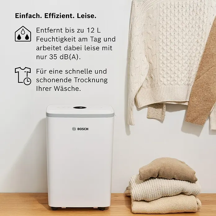 Bosch Luftentfeuchter Dry 2000 - Entfeuchtungsleistung: 12 l/Tag, Weiß - Das Bild zeigt einen Bosch Luftentfeuchter vor einem Hintergrund mit Wäsche und Textilien.
