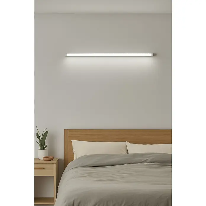 Alverlamp Regleta LED decorativa - 40 W, L x An x Al: 120 x 7,5 x 2,5 cm, Blanco cálido - Una lámpara de dormitorio moderna sobre una cama de madera con ropa de cama gris y mesita de noche, proporcionando una iluminación indirecta brillante.