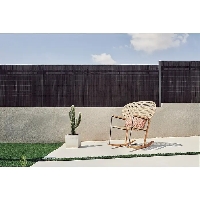 Nortene Sichtschutz LOP - Anthrazit, L x H: 300 x 150 cm - Sessel aus Rattan mit Kissen und Kaktus im Topf vor einem Zaun im Außenbereich.