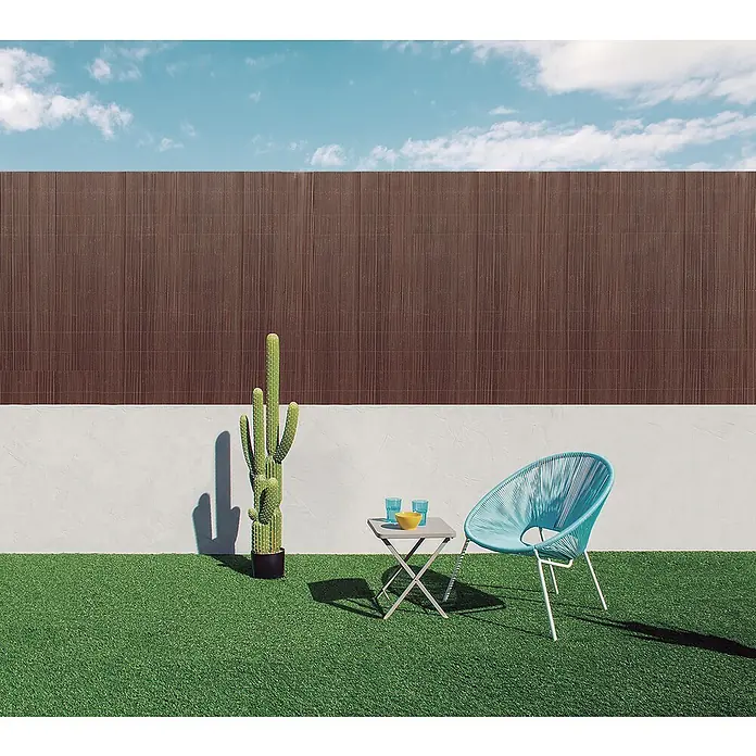 Nortene Sichtschutzmatte LOP - L x H: 300 x 90 cm - Ein blauer Stuhl und ein Tisch mit Gläsern und einer Schüssel stehen auf dem Rasen vor einer Wand mit braunem Sichtschutz.