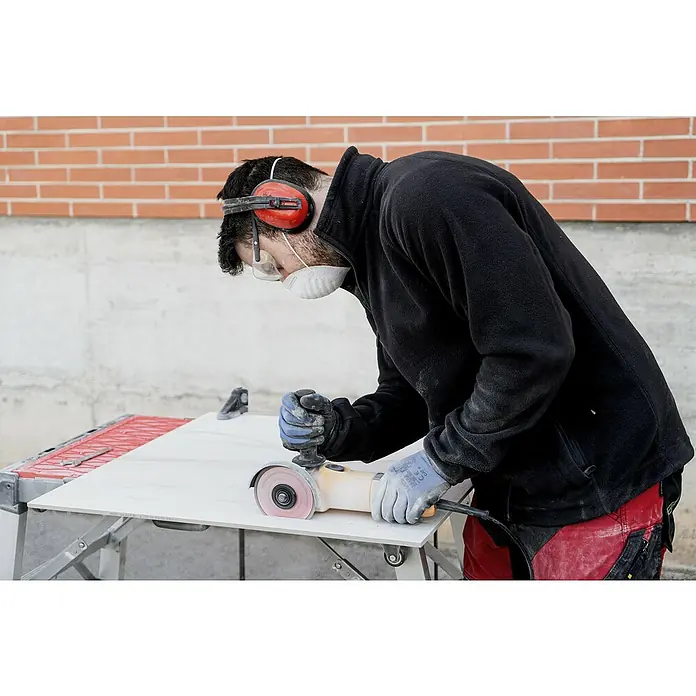 Rubi Disco de corte Slither Superpro - Ø x Es: 125 x 2,2 mm - Hombre corta azulejos con una amoladora, protegido con orejeras y máscara, asegurando un trabajo de construcción seguro.