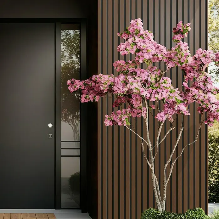Wandpaneel Outdoor - Brown, WPC, 2.350 x 219 x 26 mm - Elegante moderne Tür mit schlankem Fensterpaneel, flankiert von einer blühenden Zierpflanze und einer stilvollen Holzfassade.