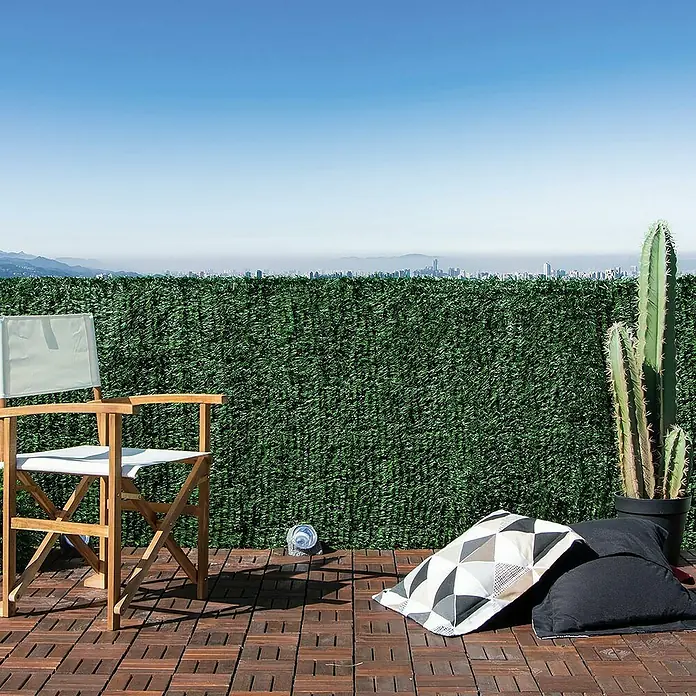 Nortene Sichtschutzmatte Hidenatur Plus - 300 x 100 cm, Kunststoff - Terrasse mit grüner Sichtschutzwand, Regiestuhl, Kissen und Kaktus. Die grüne Hecke bietet Privatsphäre und eine natürliche Atmosphäre.