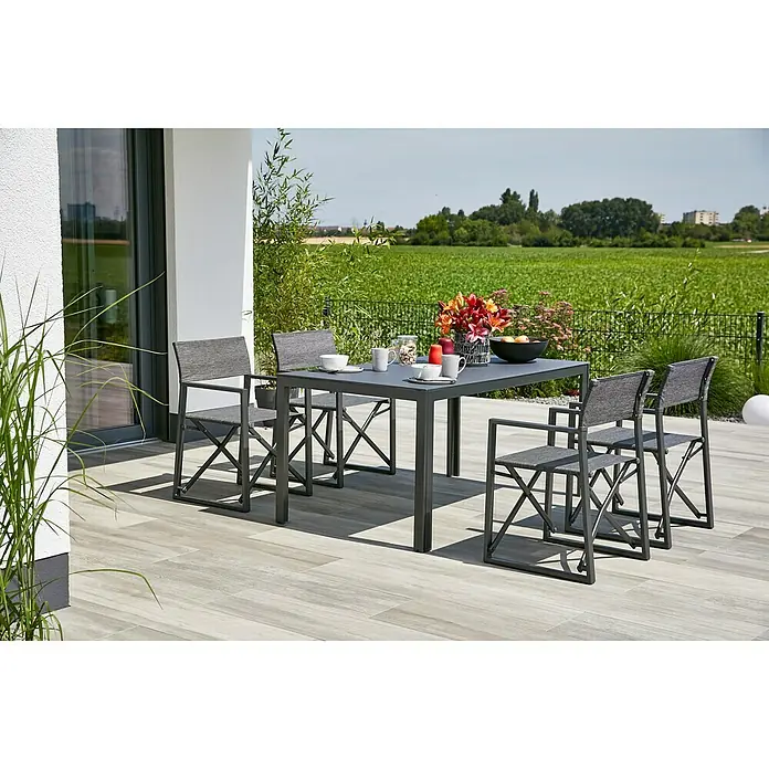 Gartenmöbel-Set Maja - 5 -tlg., Glas/Textilen/Aluminium, Anthrazit, Gartenstuhl klappbar - Ein graues Gartenset mit Tisch und vier Stühlen auf einer Terrasse mit Blick auf ein Feld, das ein modernes und stilvolles Ambiente schafft.