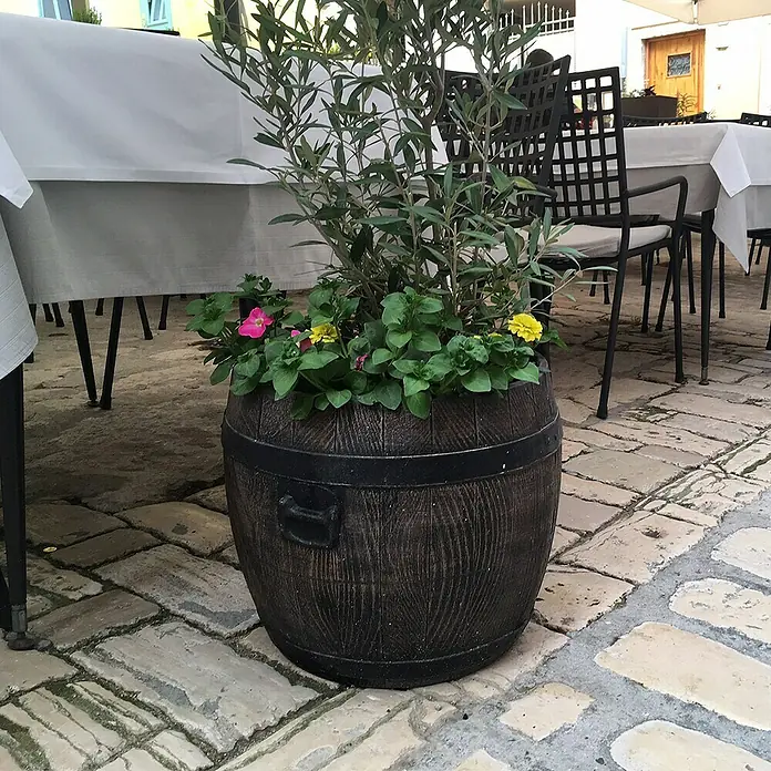 Roto Pflanztopf Bolero - Braun,Schwarz, Außenmaß (Ø x H): 70 x 68 cm, Kunststoff - Dekorative Pflanzgefäß in Form eines Holzfasses mit bunten Blumen und einem kleinen Olivenbaum, das eine rustikale Note im Freien verleiht.