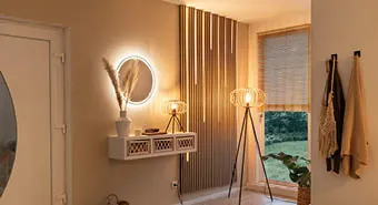 Eingangsbereich mit Akustikpnaeel und Lichtleisten an der Wand, Spiegel mit LED-Beleuchtung daneben und natürlicher Deko