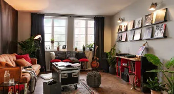 Musikzimmer mit roten Akzenten, Schallplatten an den Wänden und einem dunkelbraunen Akustikpaneel