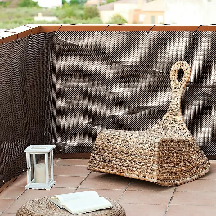 Nortene Balkonsichtschutz Balcony Easy - Anthrazit - Ein geflochtener Sessel mit hoher Rückenlehne und ein Beistelltisch mit einem Buch auf einem gefliesten Balkon.