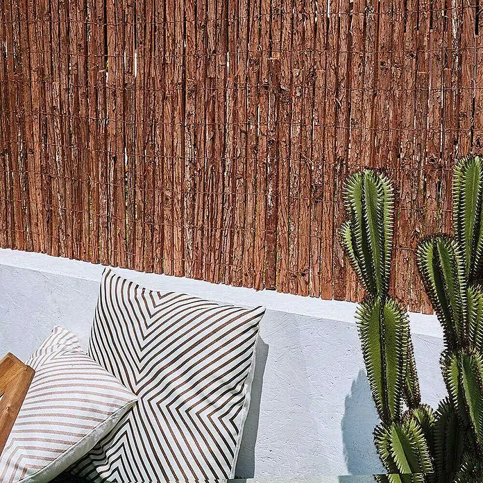 Nortene Sichtschutzmatte Corsafence - 500 x 100 cm, Holz - Diese Nahaufnahme zeigt eine dekorative Rohrwand, ergänzt durch gemusterte Kissen und einen Kaktus, ideal für den Außenbereich.