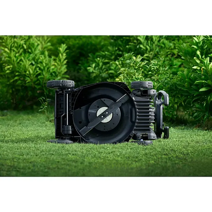 Litheli Akku-Rasenmäher EasySurge - 40 V, 2 Akkus, 4 Ah, Schnittbreite: 43 cm - Umgedrehter Rasenmäher auf Gras. Die Klingen des schwarzen Mähers sind gut sichtbar, im Hintergrund grünes Gebüsch.