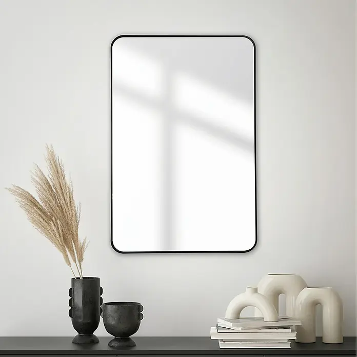Rahmenspiegel Malva - 60 x 90 cm, Schwarz - Schwarzer, gerahmter Spiegel an einer weißen Wand, neben dekorativen Vasen und Büchern für ein stilvolles Interieur.