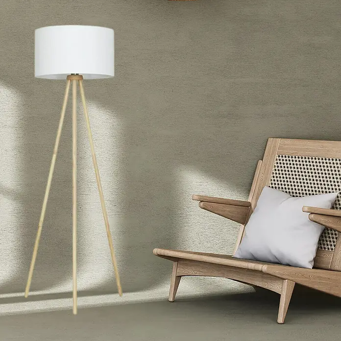 Brilo Lámpara de pie Trípode - 60 W, Altura: 1.480 mm, Blanco, E27 - Elegante lámpara de pie con pantalla blanca y patas de madera, colocada junto a un sillón con cojín para un ambiente acogedor.