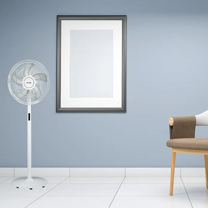 HTW Ventilador de pie SF4060 - Blanco, 40 cm, 130 cm - Imagen de un ventilador de pie moderno en una habitación con un marco de fotos y una silla.