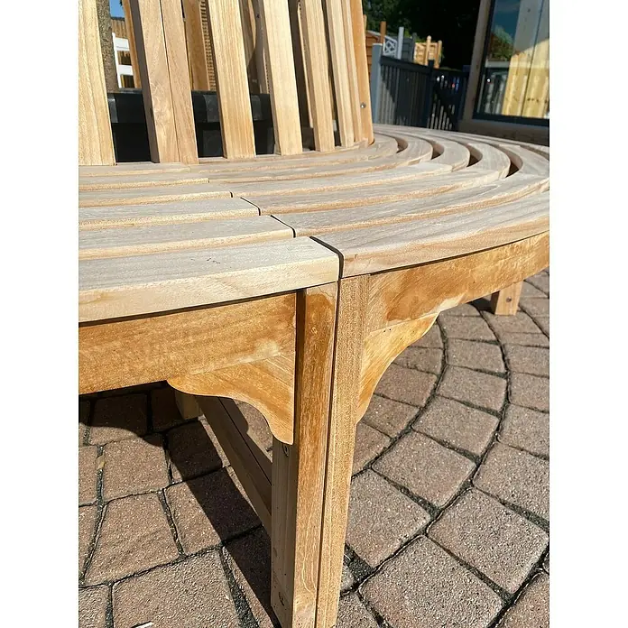 Joda Baumbank 360° - Ø x H: 220 x 90 cm, Teak, Naturbraun - Nahaufnahme einer runden Gartenbank aus Holz, die sich um einen Baum herum befindet, ideal zum Entspannen im Freien.