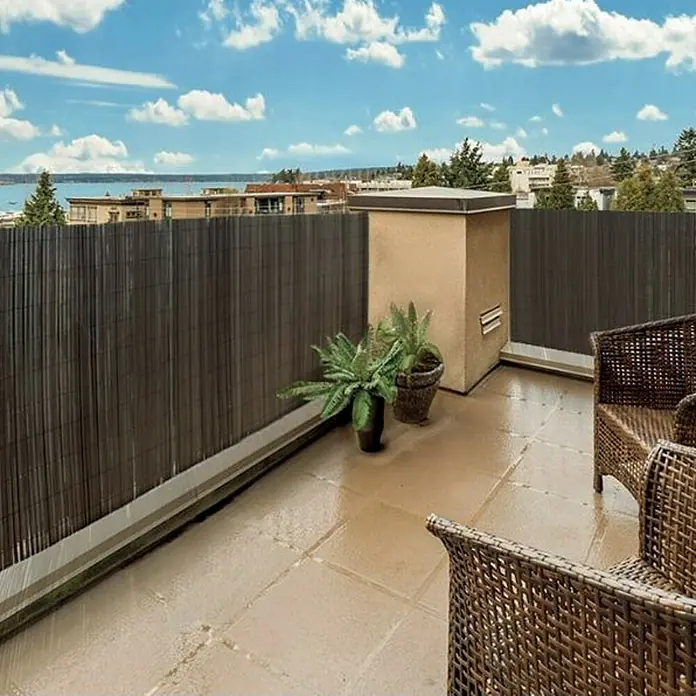 Nortene Sichtschutzmatte Surfcane - 300 x 100 cm, Anthrazit - Aufnahme einer Terrasse mit Bambuszaun, Rattansesseln und Pflanzen, die Privatsphäre und einen Hauch von Natur bieten.