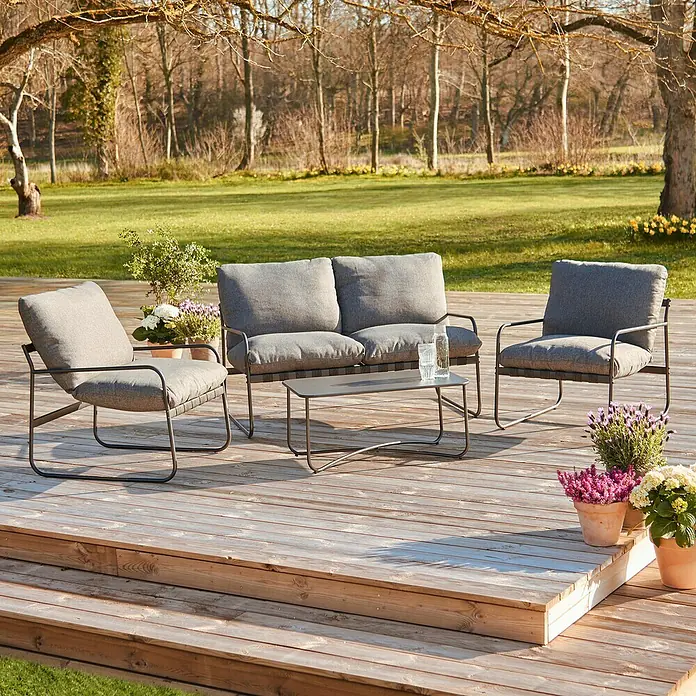 Conjunto de muebles Theodor - 4 pzs., Acero/Poliéster, Antracita - Acogedora escena al aire libre con un elegante juego de salón gris en una terraza de madera, ideal para relajarse.