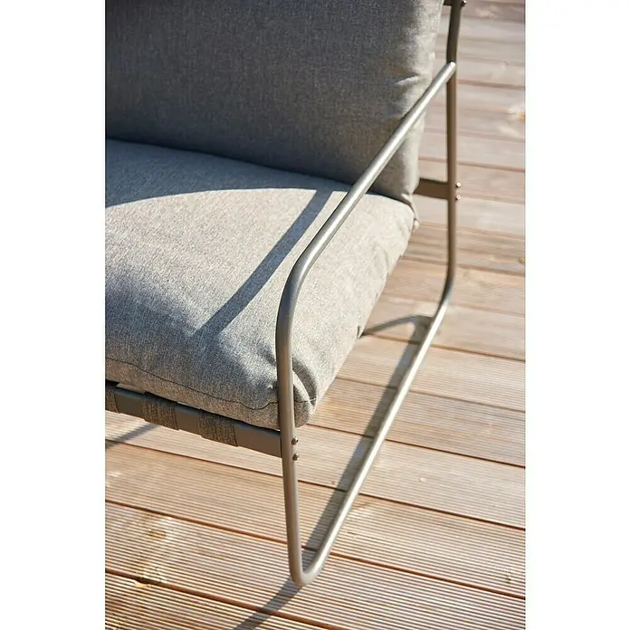 Conjunto de muebles Theodor - 4 pzs., Acero/Poliéster, Antracita - Primer plano de una silla de exterior gris con estructura metálica y cojines sobre una terraza de madera. La silla parece ideal para relajarse al aire libre.