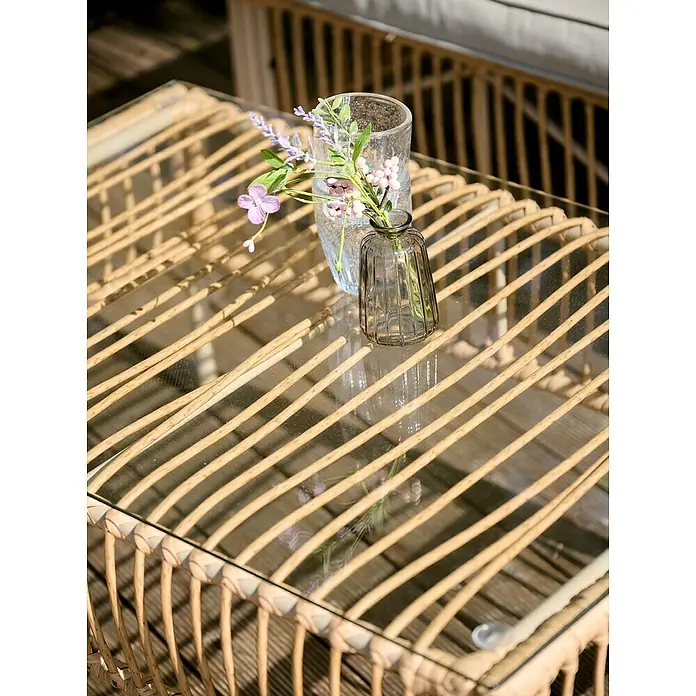 Conjunto de muebles Neel - 4 pzs., Acero/Ratán sintético, Natural/Beige - Primer plano de una mesa de centro con una tapa de vidrio y dos jarrones con flores, ideal para espacios exteriores.