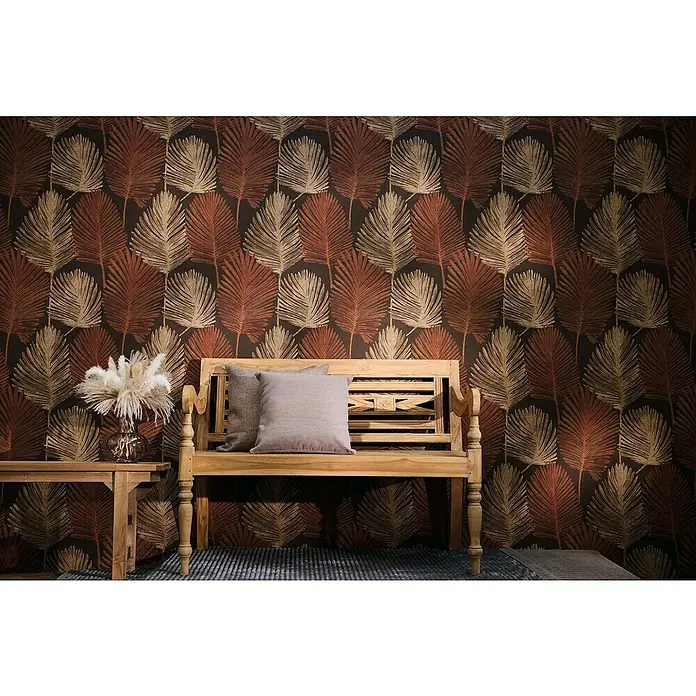 A.S. Création Metropolitan Stories Hot Spots Vliestapete Blätter - Braun-Rot-Beige, Floral, 10,05 x 0,53 m - Holzbank mit Kissen und Beistelltisch mit Blumenvase vor einer Tapete mit Blattmuster.