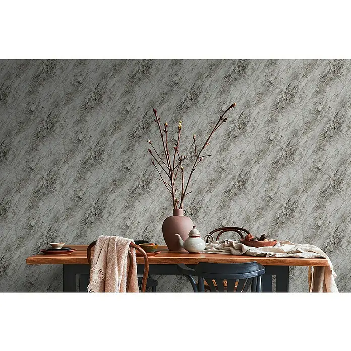 A.S. Création Metropolitan Stories Vliestapete Marmor - Grau/Schwarz, L x B: 10,05 x 0,53 m - Dekoratives Esstableau mit Keramikvase, Geschirr und Textilien auf einem Holztisch vor einer grauen Marmorwand für ein stilvolles Ambiente.