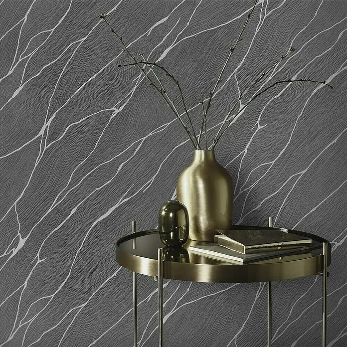 Papel pintado Texturado Mármol - Negro, Efecto piedra, 10 x 0,53 m - Primer plano de una mesa auxiliar de bronce con detalles dorados, libros y jarrones contra una pared texturizada.