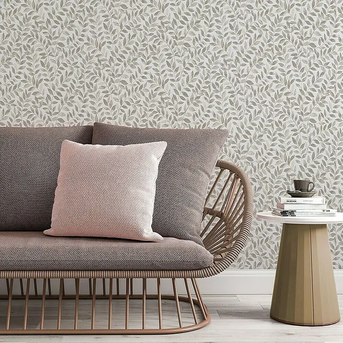 Papel pintado Hojas Vegetal - Marrón, Floral, 10 x 0,53 m - Primer plano de un elegante sofá con cojines decorativos y una mesa auxiliar con un libro y una taza, con un papel pintado de hojas de fondo.