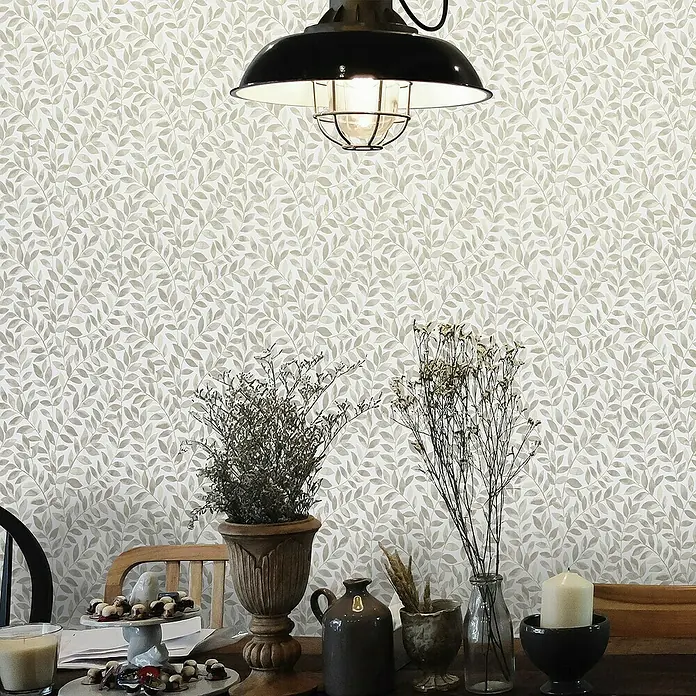 Papel pintado Hojas Vegetal - Marrón, Floral, 10 x 0,53 m - Primer plano de una mesa con elementos decorativos como plantas, velas y platos frente a una pared estampada con hojas.