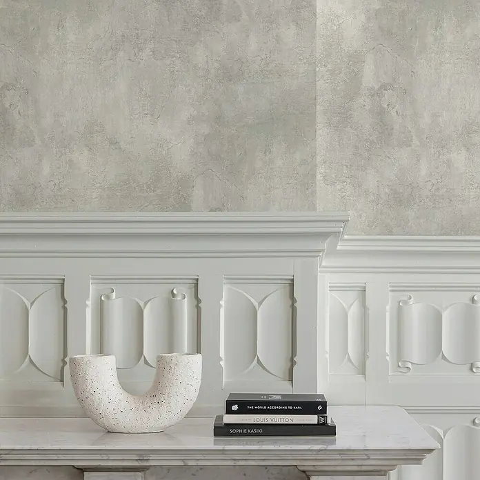 Papel pintado Liso Texturado - Gris, Unicolor, 10 x 0,53 m - Un objeto decorativo curvado de cerámica blanca y libros sobre una chimenea, frente a una pared gris.