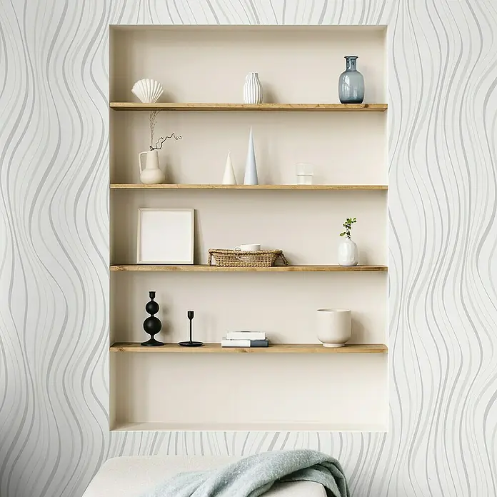 Papel pintado Ondas - Blanco, Ondas, 10 x 0,53 m - Elegante estantería con decoraciones que incluyen conchas, jarrones y velas, enclavada en una pared con un elegante patrón ondulado.