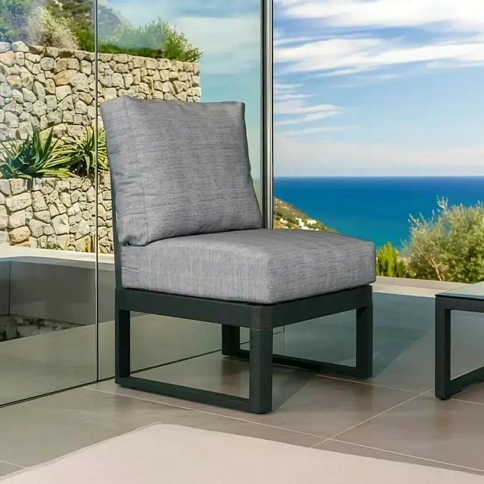 Bonlay Loungesofa-Mittelelement Nova - B x T x H: 58 x 65 x 85 cm, Aluminium, Textilene, Anthrazit - Ein grauer Outdoor-Sessel mit Kissen steht vor einer Glaswand und bietet einen Blick auf das Meer. Der Sessel hat ein modernes Design mit einem robusten Rahmen.