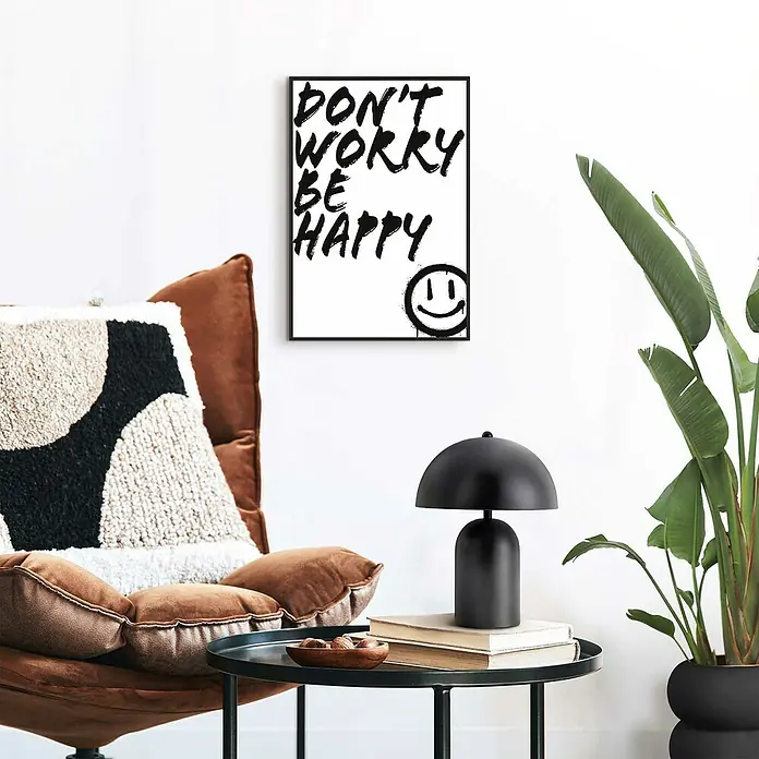 Reinders Bild Slim Frame - Don´t Worry, B x H: 20 x 30 cm - Schwarze Nachttischlampe mit pilzförmigem Design auf einem Beistelltisch mit Büchern und einer Schale, neben einem Sessel und einem gerahmten Poster.