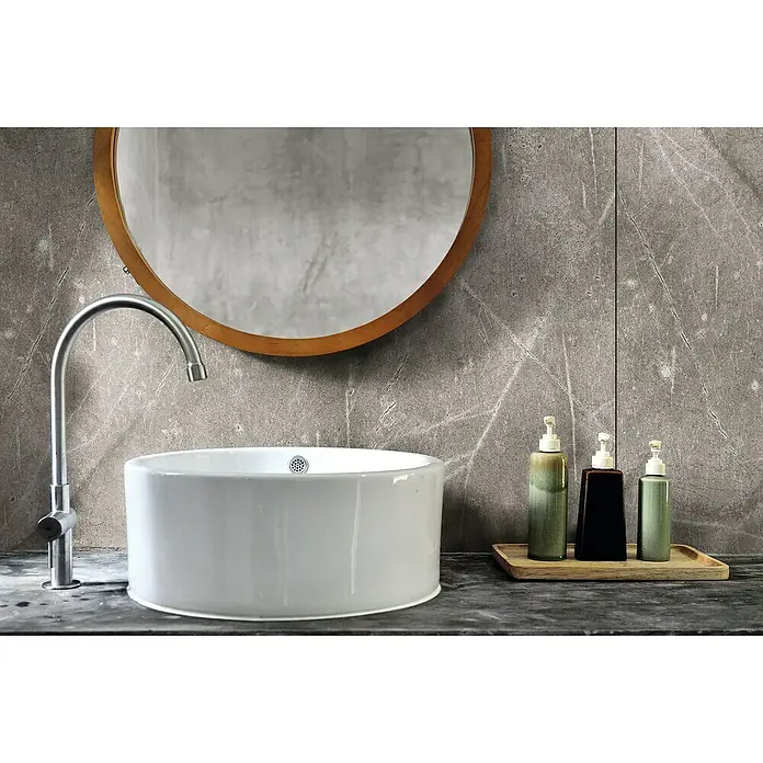 LOGOCLIC Wandpaneel Designwall - Grey Atlantic Marble, 265 x 123 cm - Stilvolles Badezimmer Waschbecken mit Armatur und Seifenspender auf einer Ablage, ergänzt durch einen runden Spiegel an der Wand.