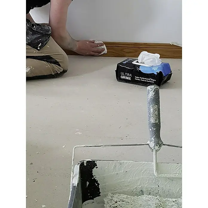 Feuchte Reinigungstücher Ultra Grime - 100 Stk. - Ein Arbeiter wischt einen Sockel mit Ultra Grime Tüchern ab. Die Tücher sind speziell für Handwerker geeignet.
