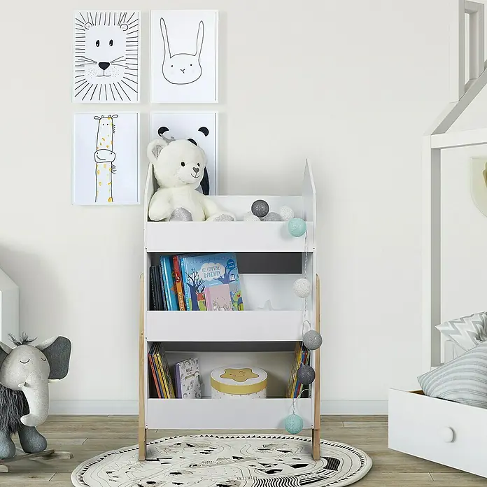 Home Deco Kids Estantería de madera Casita -  - Esta foto muestra una estantería blanca de tres estantes, llena de libros y juguetes, sobre una pared blanca.