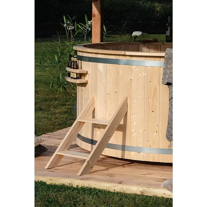 Tuindeco Hot Tub - 200 cm, Fichte, Natur, Max. Personenzahl: 6 Stk. - Holzbeheizter Badezuber mit Leiter und Bierhaltern auf einer hölzernen Terrasse.