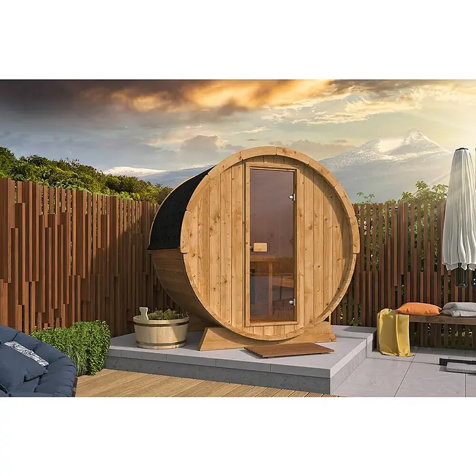 Tuindeco Fasssauna - L x B x H: 205 x 160 x 205 cm, Ohne Ofen - Das Bild zeigt eine Fasssauna im Freien mit Holzwänden, einer Glastür und Blick auf die Berge. Die Sauna ist aus hellem Holz gefertigt.