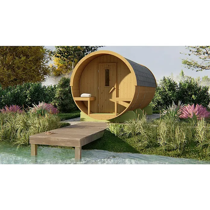 Tuindeco Fasssauna - L x B x H: 400 x 205 x 220 cm, Ohne Ofen - Eine Fasssauna aus Holz steht am Ufer mit einem kleinen Steg im Grünen. Die Sauna hat ein graues Dach und ist für den Außeneinsatz konzipiert.