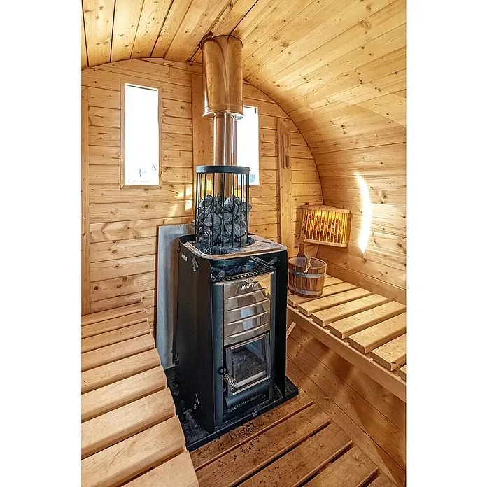 Tuindeco Saunaleuchte - 60 W, Holz - Innenansicht einer Sauna mit einem Harvia-Holzofen, Steinen und Bänken, die ein entspannendes und authentisches finnisches Saunaerlebnis versprechen.