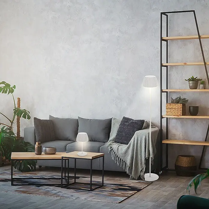 Brilo Riffle Akku-Stehleuchte Maxi - Ø x H: 19 x 124,1 cm, Weiß, Warmweiß, 4,2 W, IP44 - Elegante Studioaufnahme eines modernen Wohnraums mit einem grauen Sofa, zwei Beistelltischen und zwei dekorativen Lampen.