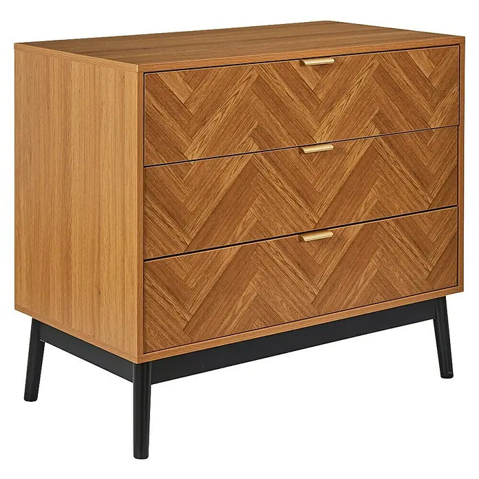 Home Deco Factory Felix Cómoda con mesitas - 3 pzs., Marrón/Negro, Acabado en espiga - La imagen muestra una moderna cómoda de madera con tres cajones y tiradores dorados sobre un marco de metal negro. La cómoda tiene un patrón de espiga en los cajones.